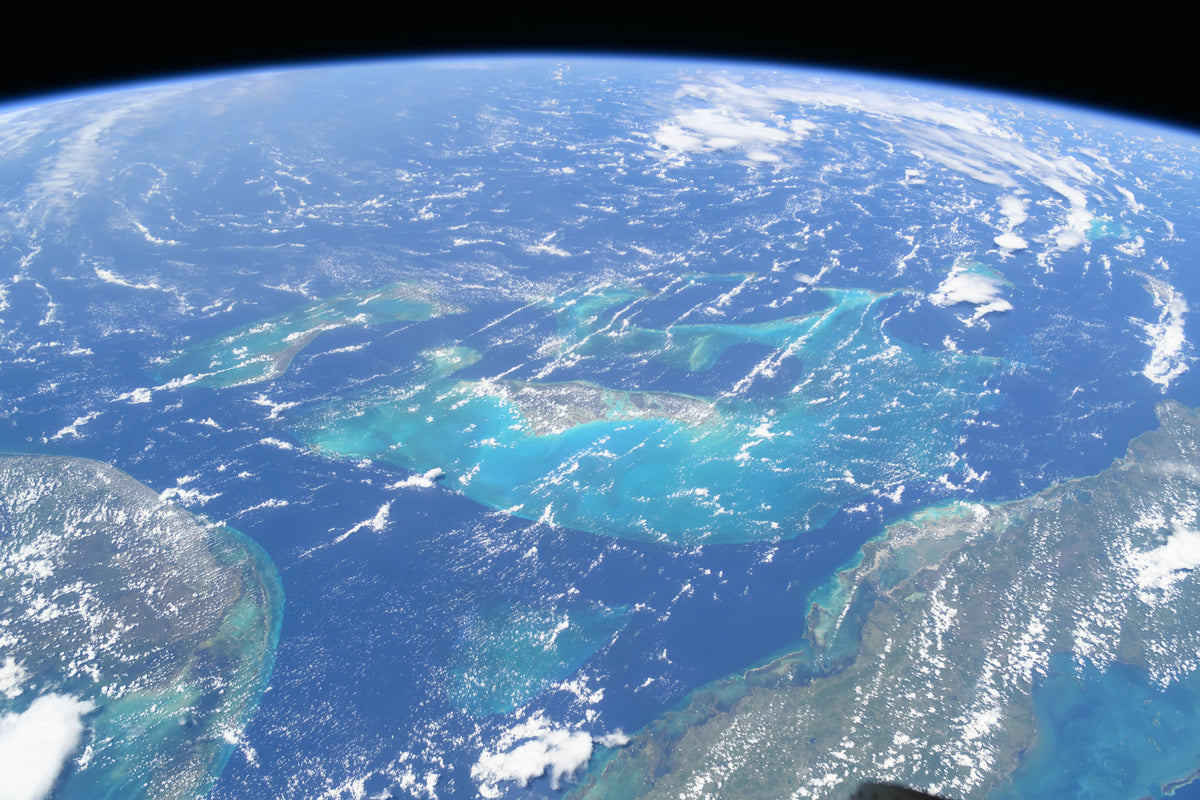 Blue Atlantic waters and green islands of The Bahamas under Earth's horizon, seen from the International Space Station. Photo: NASA (ISS071-E-449837)